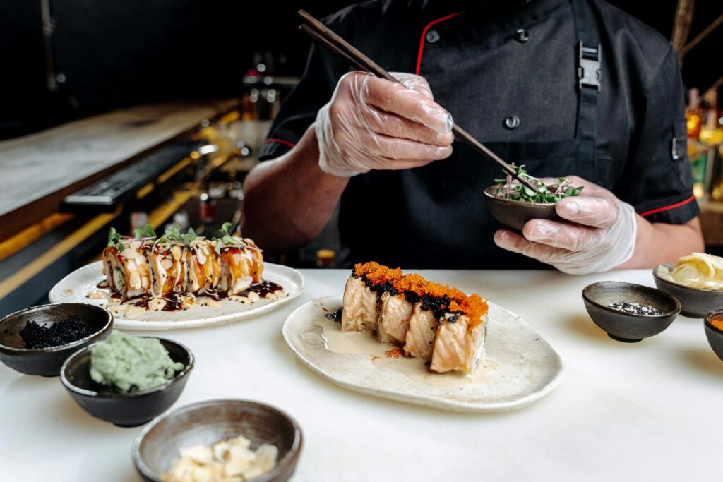 A chef in action creating beautifully garnished sushi rolls in a modern restaurant setting.